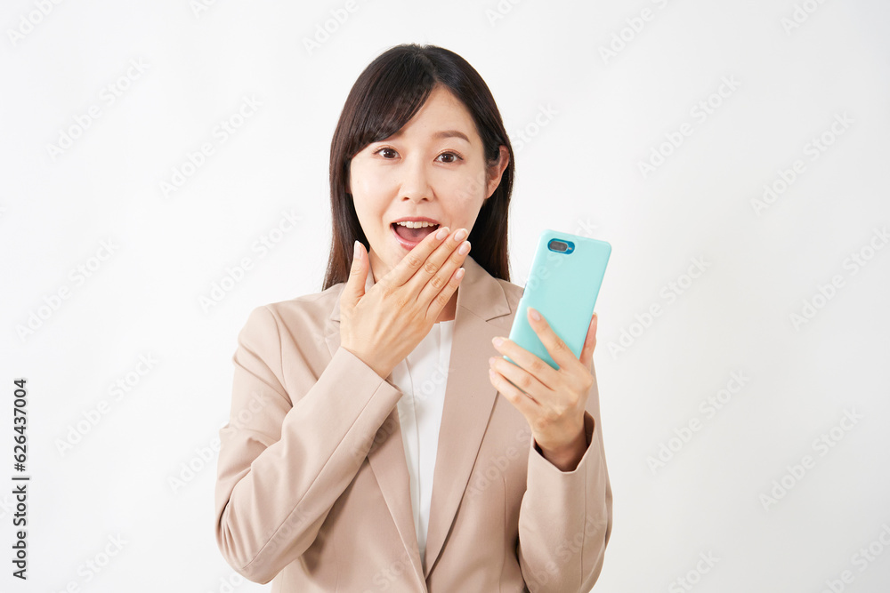 スマートフォンを持って驚くミドルエイジのビジネスウーマン 白背景 スマートフォンを持って驚くミドルエイジのビジネスウーマン 白背景