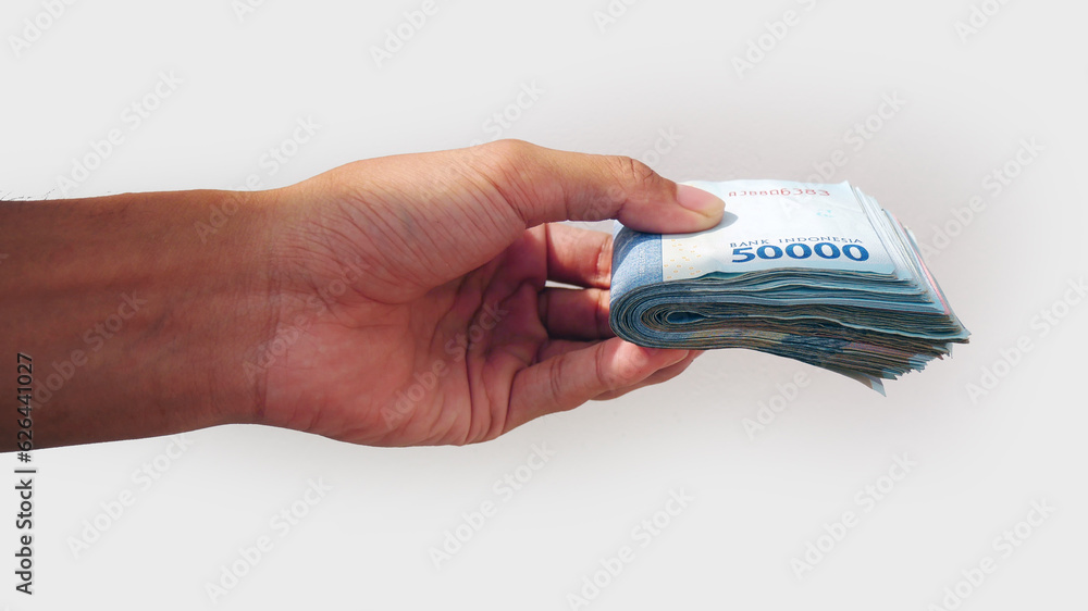 Asian hand giving some money in Indonesian currency on a white background Asian hand giving some money in Indonesian currency on a white background