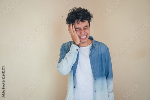 Young curly man wear denim clothes feel toothache and painful. The photo is suitable to use for man expression advertising and fashion life style.