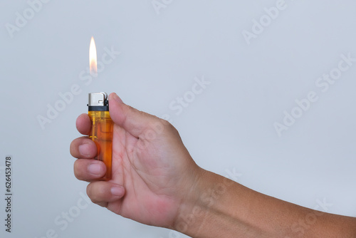 Hand holding a flaming gas lighter over white background