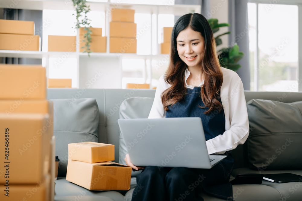 Young asian business owner woman prepare parcel box and standing check online orders for deliver to customer on tablet, laptop Shopping Online concept.. Young asian business owner woman prepare parcel box and standing check online orders for deliver to customer on tablet, laptop Shopping Online concept..