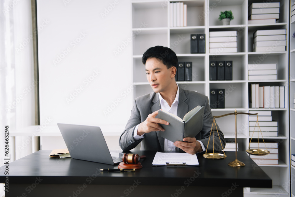 Asian man lawyer reading legal book with gavel on table in office. justice and law ,attorney concept. Asian man lawyer reading legal book with gavel on table in office. justice and law ,attorney concept.