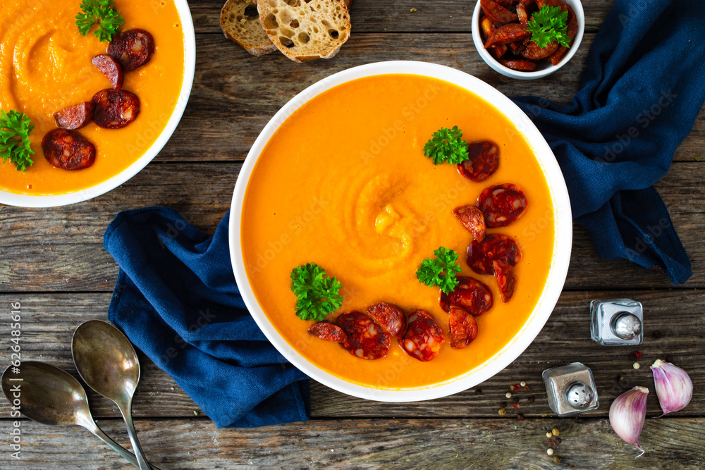 Sweet potatoes cream soup with choriso sausage on wooden background, top view Sweet potatoes cream soup with choriso sausage on wooden background, top view