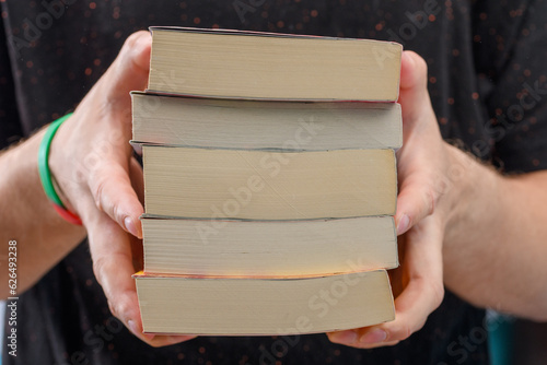 Student trzyma w dłoniach stos książek 