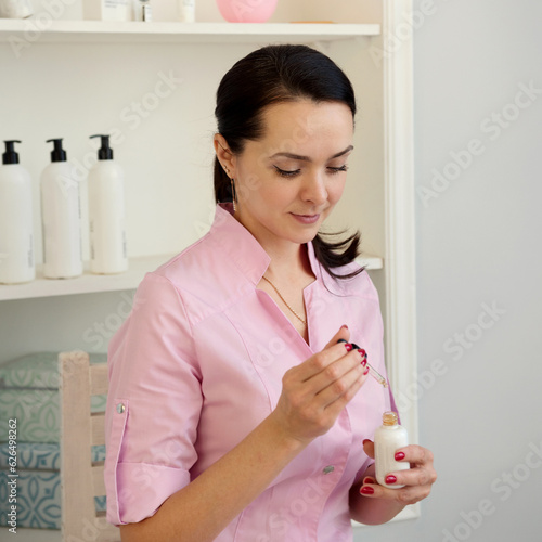 beautiful young woman applying cream on her face in the beauty salon