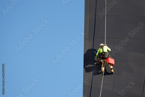 Window cleaner working on a glass facade suspended. Heavy work concept photo