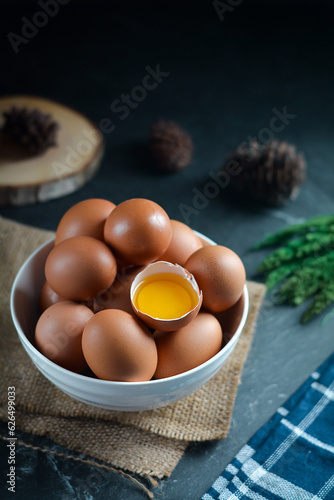 egg on the bowl in dark texture background. one broken egg among eggs in teh bowl.
