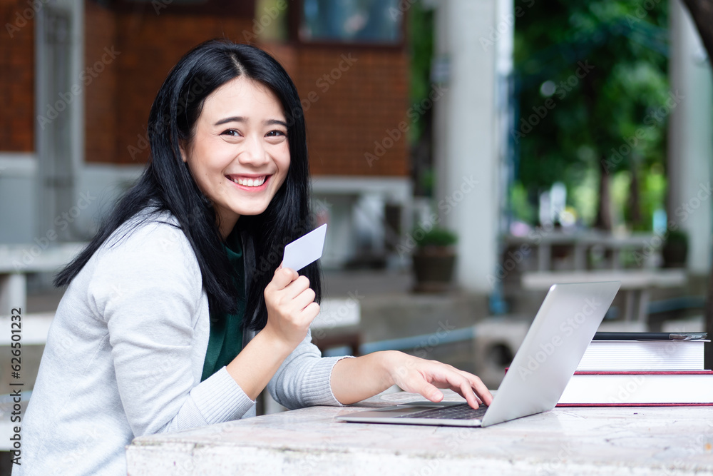 Happy smiling Asian female student holding blank card, concept of student ID card, educational purpose credit card, student loan, scholarship money, educational financial credit Happy smiling Asian female student holding blank card, concept of student ID card, educational purpose credit card, student loan, scholarship money, educational financial credit