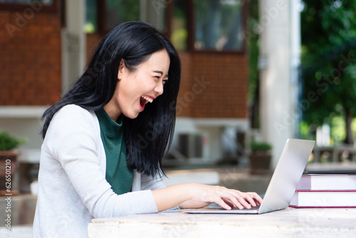 Excited and happy Asian College Student Using Laptop for Educational Purpose, Back to School with internet technology, remote learning or e-learning Concept © 9nong