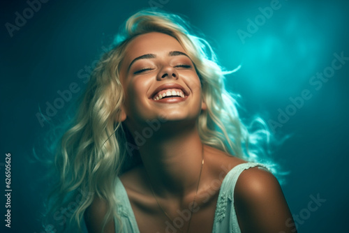 Content teen blonde smiling on turquoise background, dark light photography
