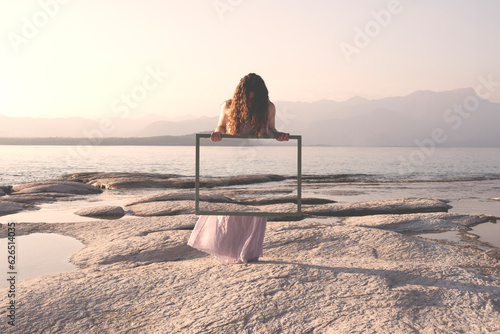 Photography woman holding a frame that surreally reflects the landscape , concept of door to