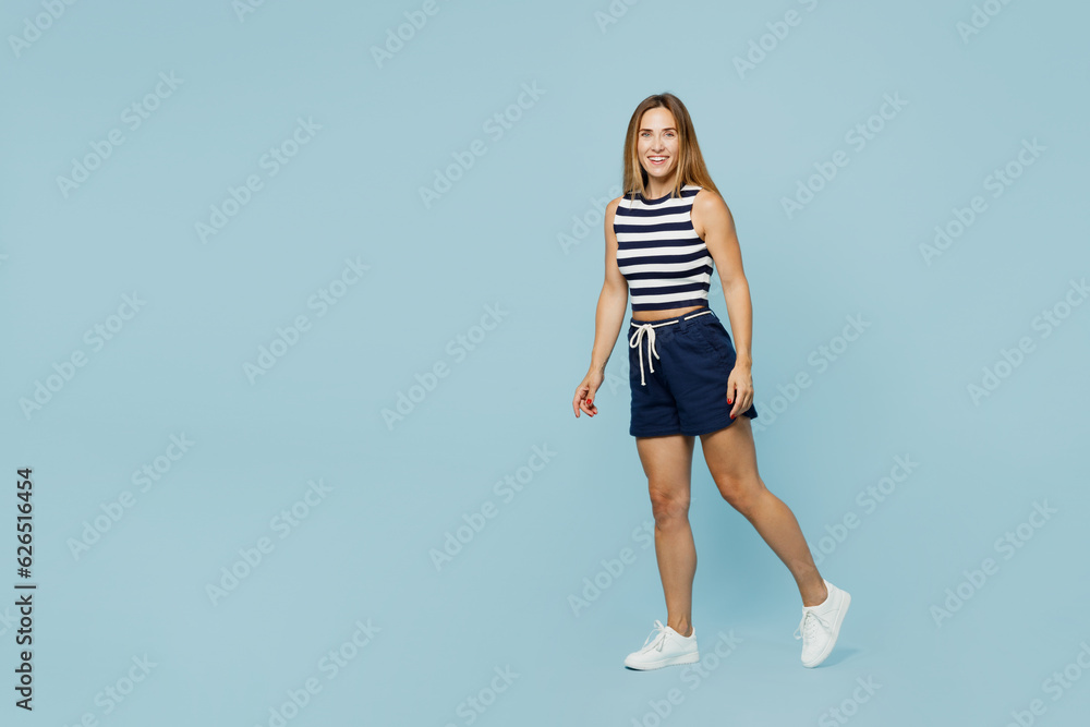 Full body sise view smiling happy fun young woman she wear striped tank shirt casual clothes looking camera walking going isolated on plain pastel light blue cyan background studio. Lifestyle concept. Full body sise view smiling happy fun young woman she wear striped tank shirt casual clothes looking camera walking going isolated on plain pastel light blue cyan background studio. Lifestyle concept.