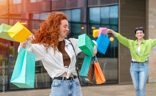 women with colorful bags having fun time with shopping in urban city. Consumerism, sale, purchases, shopping, lifestyle concept.