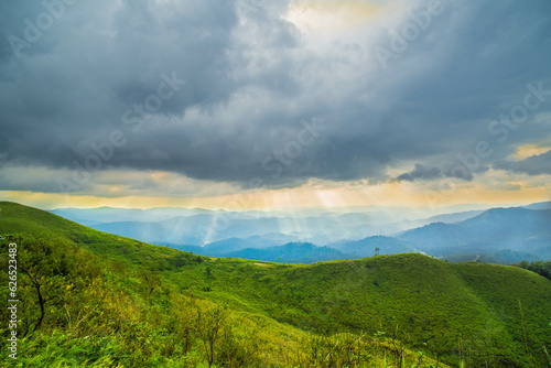 The breathtaking view in Kanchanaburi, Thailand, as seen from the point of view of a tourist, being surrounded by mountains and a golden sky in the background.