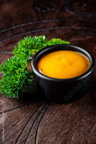 Fresh homemade organic mustard sauce in bowl on wooden background
