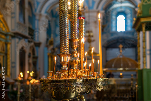 Lighted candles in the Orthodox Church against the background of icons and interiors of the temple