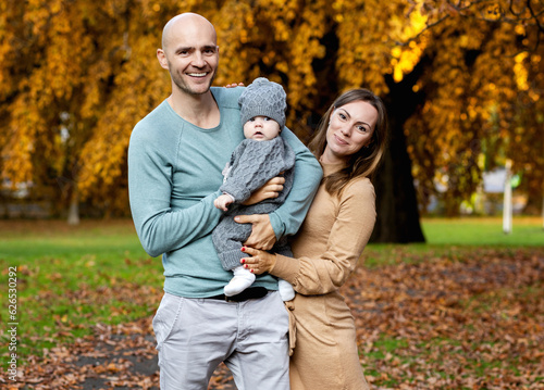 Happy parents of the firstborn in the park on a day off in autumn