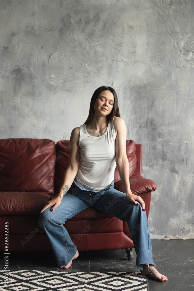 Portrait of a young attractive girl in a white T-shirt and jeans. A girl of oriental appearance in the interior of a stylish apartment. Lifestyle Portrait of a young attractive girl in a white T-shirt and jeans. A girl of oriental appearance in the interior of a stylish apartment. Lifestyle