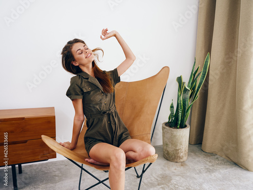 Woman model sits on a chair at home smile, fun and relaxation, modern stylish interior scandia lifestyle, copy space. photo