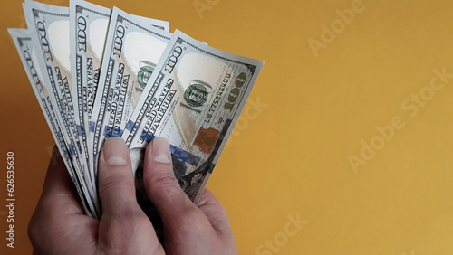 Close-up of female hands holding a pack of one hundred dollar bills.The concept of paying for goods and services, getting paid, bribes.American currency,copy space.