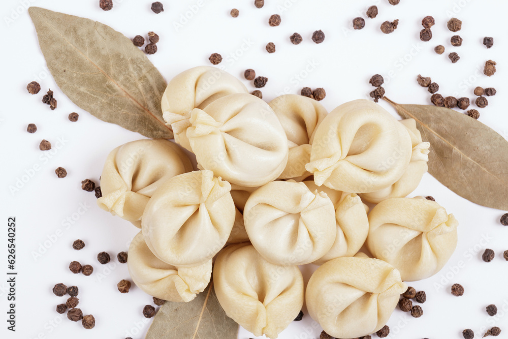 Uncooked dumplings with peppercorns and bay leaves on white background. Dumplings closeup. Top view. Uncooked dumplings with peppercorns and bay leaves on white background. Dumplings closeup. Top view.