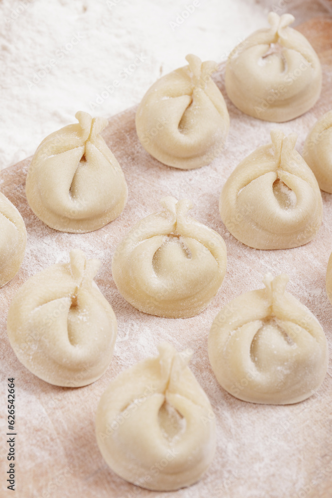 Uncooked dumplings on the wooden board. Homemade dumplings closeup. Macro shot.