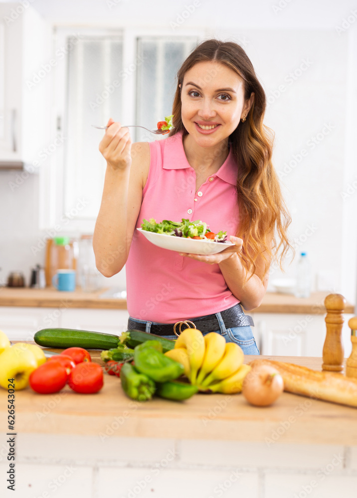 Smiling young woman enjoying salad at home Smiling young woman enjoying salad at home