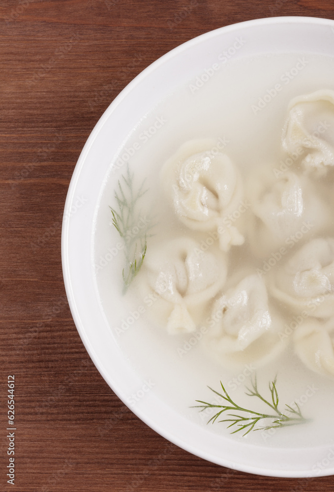 Bouillon with homemade pelmeni and fresh dill. Soup with dumplings and herbs. Top view. Bouillon with homemade pelmeni and fresh dill. Soup with dumplings and herbs. Top view.