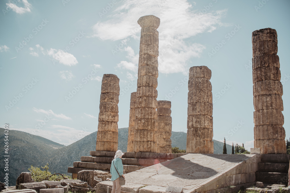 Backview of a tourist looking at the Temple of Apollo in Delphi, Greece