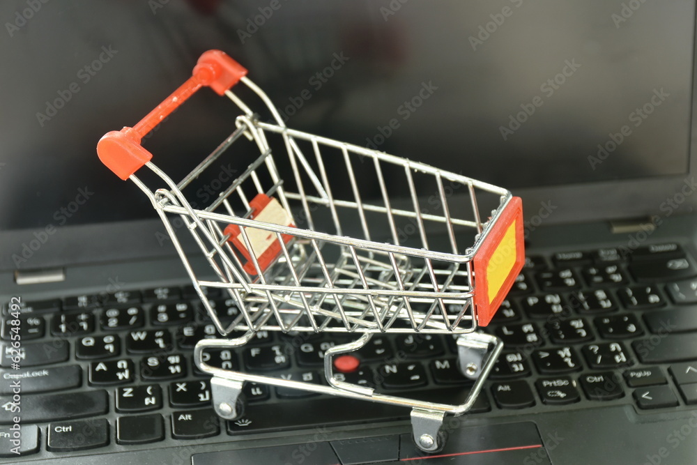 small shopping cart on laptop and computer screen background concepts shop on line