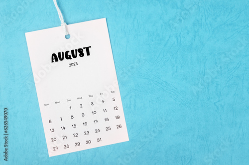 The 2023 August calendar page hanged on white rope  on blue background.