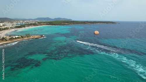 Aerial view of people enjoying parasailing in Sa Coma beach in Mallorca, Spain on a summer day