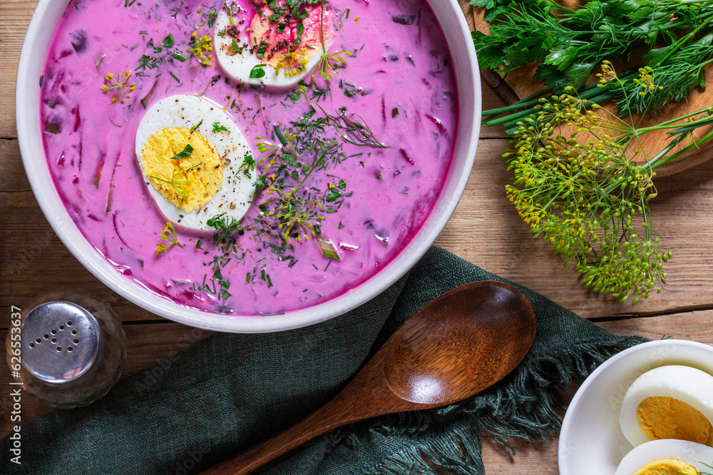 Traditional summer cold beetroot soup with cucumber, egg and sour cream on a wooden background. Rustic style.