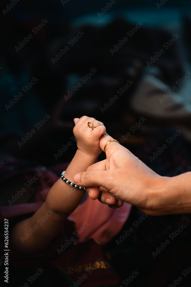 baby holding finger of her mother 