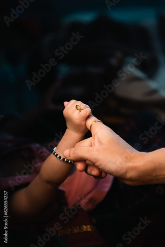 baby holding finger of her mother 