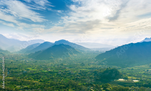 landscape of green summer highland mountain range with green beautiful valley below and amazing blue cloudy sky