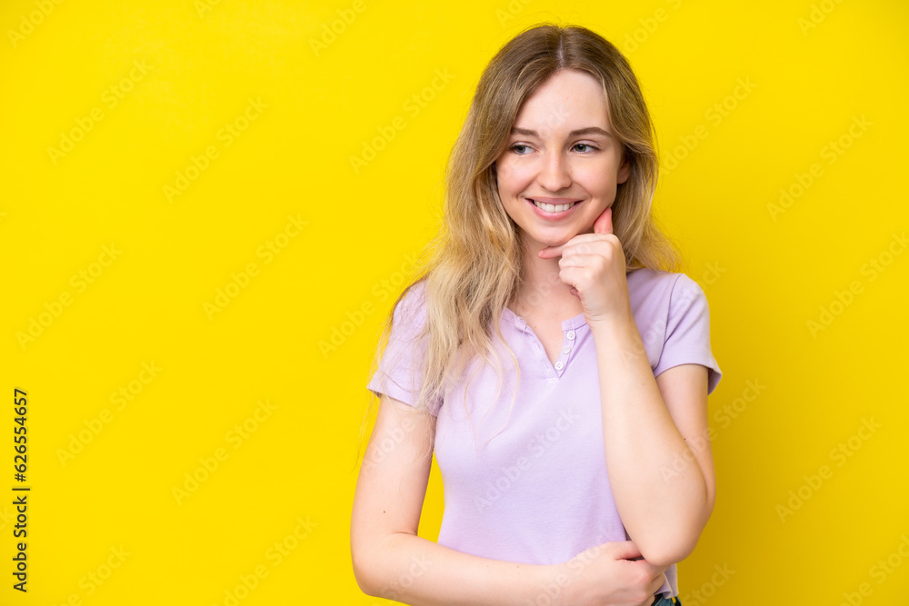 Blonde English young girl isolated on yellow background looking to the side and smiling Blonde English young girl isolated on yellow background looking to the side and smiling