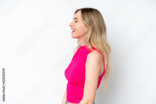 Blonde English young girl isolated on white background laughing in lateral position