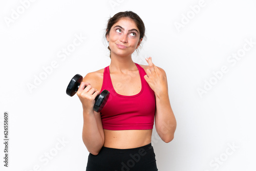 Young sport caucasian woman making weightlifting isolated on white background with fingers crossing and wishing the best