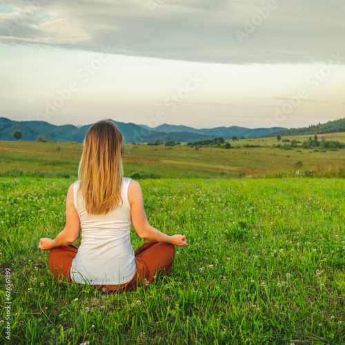 Woman doing yoga on the green grass at the mountain. Carpathians