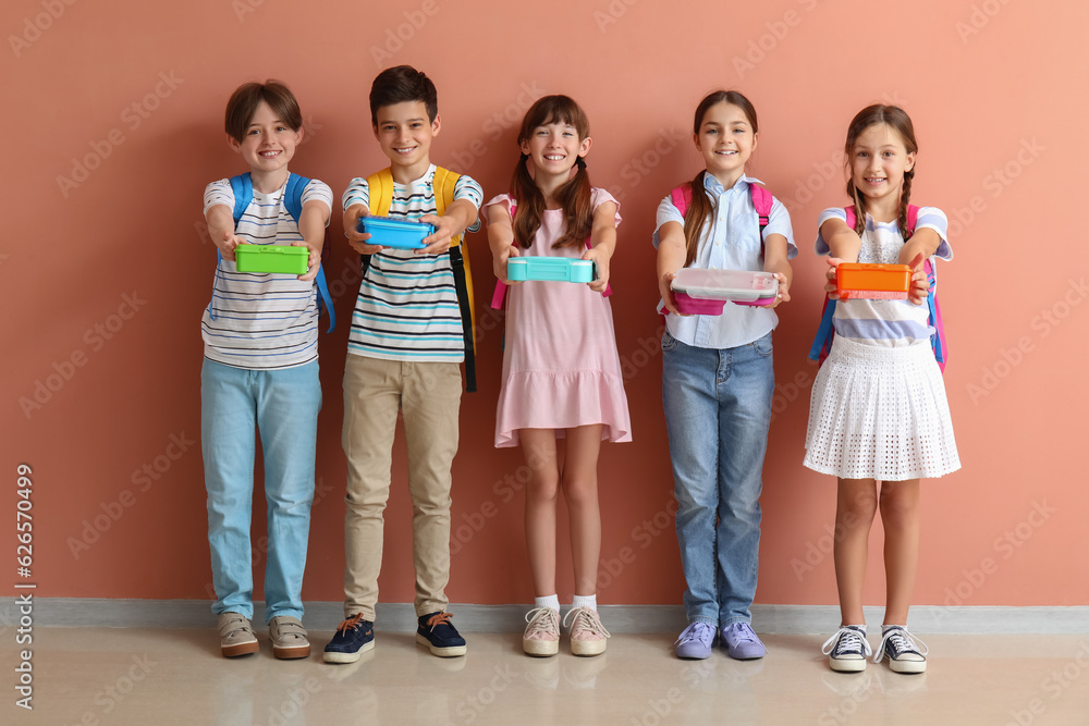 Little pupils with lunchboxes and backpacks near pink wall Little pupils with lunchboxes and backpacks near pink wall