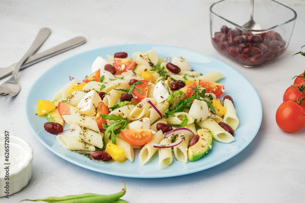 Plate of tasty pasta salad with tomatoes and beans on white background Plate of tasty pasta salad with tomatoes and beans on white background