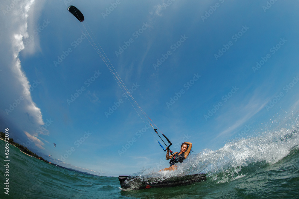 Obraz premium Female Kite surfer riding a kiteboard on the sea with splash.