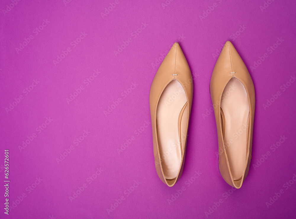 Top view of elegant beige women's shoes with pointed, decorated with stitches in front, toes isolated on a bright purple background with copy space. Shoe sale, clearance ad concept. Top view of elegant beige women's shoes with pointed, decorated with stitches in front, toes isolated on a bright purple background with copy space. Shoe sale, clearance ad concept.