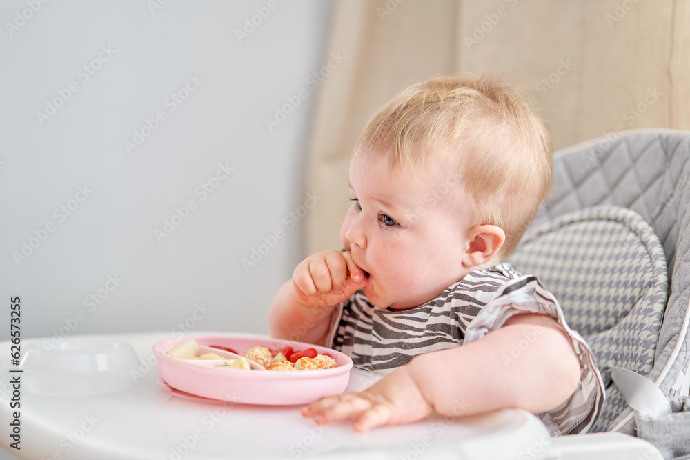 Cute child eats healthy food vegetables and meatballs from dietary meat steamed,. Portraits of a cute 10 months old baby girl. The baby sitting in a special high chair for babies. Cute child eats healthy food vegetables and meatballs from dietary meat steamed,. Portraits of a cute 10 months old baby girl. The baby sitting in a special high chair for babies.