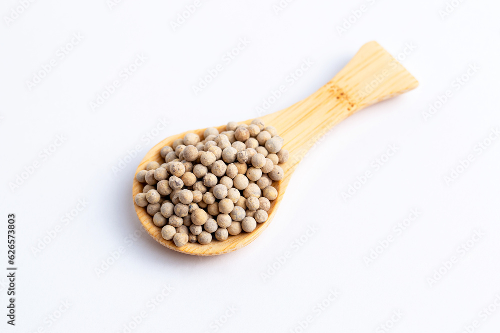 White pepper seeds in wooden spoon isolated on white background. White pepper seeds in wooden spoon isolated on white background.