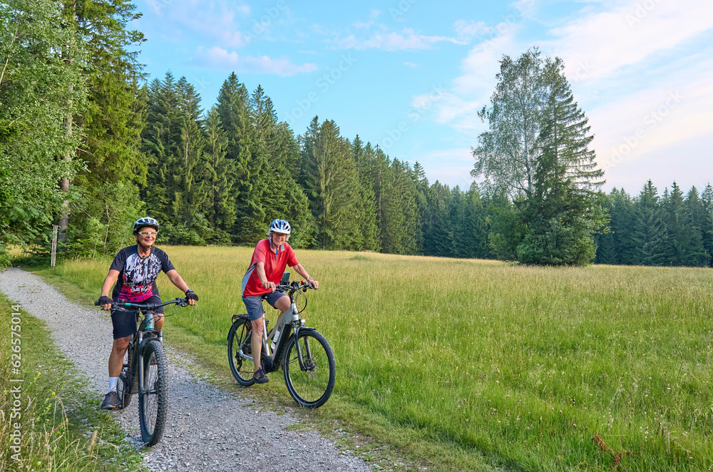 two senior girlfriends having fun during a cycling tour in the Allgau Alps near Oberstaufen, Bavaria, Germany