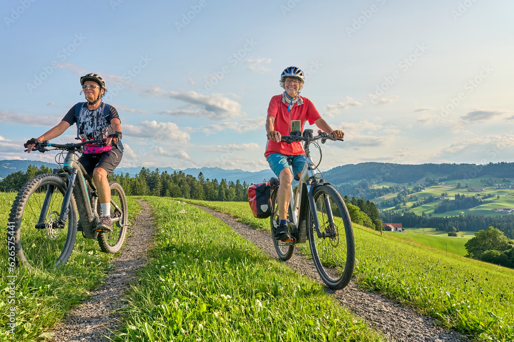 Naklejka premium two senior girlfriends having fun during a cycling tour in the Allgau Alps near Oberstaufen, Bavaria, Germany