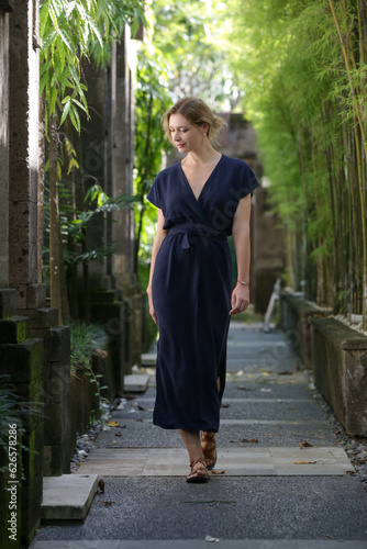 Outdoor portrait of stylish fashionable woman in dark blue linen dress. Casual yet stylish summertime outfit, spring-summer fashion trend, tropical vacation style.