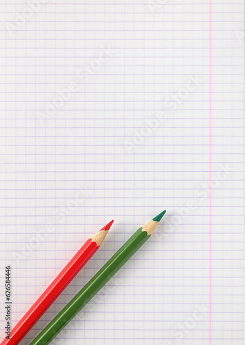 checkered notebook sheet and two colored pencils, copy space